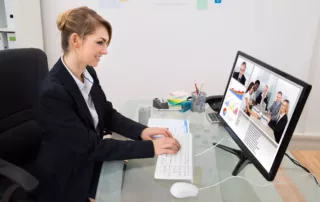 Young Happy Businesswoman At Desk Video Conferencing On Computer - Miedema's Board Consulting Toronto